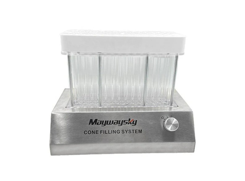 Op de afbeelding: Een roestvrijstalen kegelvulsysteem met een transparante kunststofkamer en een wit deksel. Het systeem heeft een knop om de temperatuur te regelen en de tekst "Maywaysky CONE FILLING SYSTEM" staat op de voorkant.