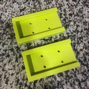 Op de afbeelding: Twee limoengroene plastic wandbevestigde zeepbakjes met elk vier gaten.