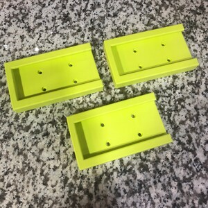 Op de afbeelding: Drie limoengroene plastic zeepbakjes met drie gaten in elk. De bakjes zijn op elkaar gestapeld.