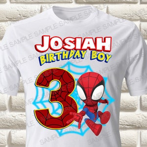 May include: White t-shirt with a Spider-Man cartoon design. The shirt displays the name "JOSIAH" in red, the words "BIRTHDAY BOY" in blue, and the number "3" in a web design. A cartoon Spider-Man character is also present.