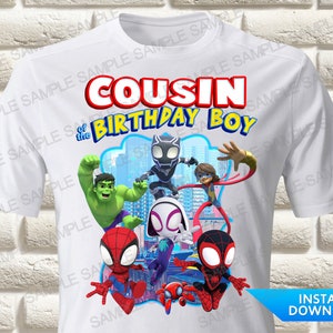 Peut inclure: T-shirt blanc avec un graphique de Spider-Man, Hulk, Black Panther et une fille aux cheveux roux. Le texte "Cousin du garçon d'anniversaire" est imprimé en lettres bleues et rouges.