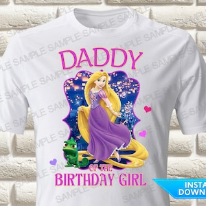 May include: White t-shirt with a pink and purple design featuring Rapunzel from the Disney movie Tangled. The design includes a purple frame with Rapunzel's hair flowing down, a green chameleon, and the text "Daddy of the Birthday Girl".