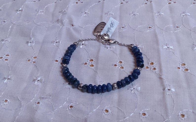 Puede incluir: Pulsera de cuentas azules oscuras y cuentas de metal plateado. La pulsera tiene un cierre plateado y una etiqueta con la palabra "Brighton". Las cuentas son peque&ntilde;as y redondas.