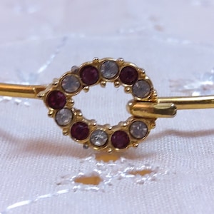 May include: A gold bracelet with a circle of pink and clear rhinestones.