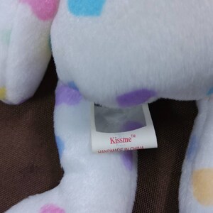 May include: White plush toy with colorful polka dots. The toy has a tag that reads "Kissme" and "Handmade in China".
