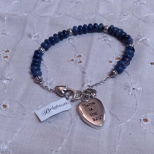 Puede incluir: Una pulsera de cuentas azules con detalles plateados y un dije en forma de coraz&oacute;n con la inscripci&oacute;n "Love is the key". La pulsera tiene un cierre plateado y una etiqueta "Brighton".