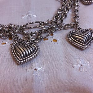 Pu&ograve; includere: Una collana a catena d'argento con pi&ugrave; ciondoli a forma di cuore. Ogni cuore ha un design testurizzato e nervato.
