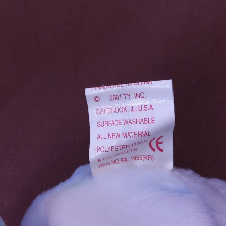May include: White tag with pink text stating "Handmade in China", "2001 TY INC., Oakbrook, IL. U.S.A.", "Surface Washable", "All New Material", "Polyester Fiber & PE. Pellets", "Reg. No. PA. 1965(KR)" and a CE mark.
