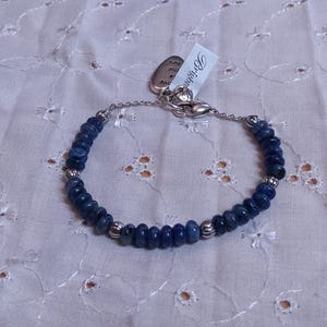 Puede incluir: Una pulsera de cuentas azules oscuras con detalles plateados y un cierre. La pulsera presenta peque&ntilde;as cuentas redondas de color azul oscuro ensartadas. Una etiqueta con la palabra "Brighton" est&aacute; adjunta.