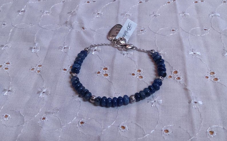 Puede incluir: Una pulsera de cuentas azules oscuras con detalles plateados y un cierre. La pulsera presenta peque&ntilde;as cuentas redondas de color azul oscuro ensartadas. Una etiqueta con la palabra "Brighton" est&aacute; adjunta.
