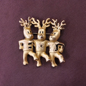 AJC Goldtone Reindeer Trio Brooch. Three Reindeer in a Chorus Line kicking up their legs. Maker's mark present.