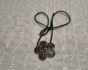 Flower Bejeweled Pendant on a Black Corded Necklace enhanced with Crystals in Iridescent shades of Red. No maker's mark found.