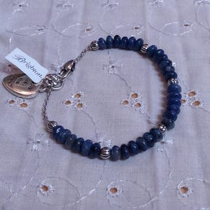 Puede incluir: Una pulsera de cuentas azules con detalles plateados y un dije en forma de coraz&oacute;n. La pulsera presenta peque&ntilde;as cuentas azules redondas y cuentas plateadas. Una etiqueta con la palabra "Brighton" est&aacute; adjunta.