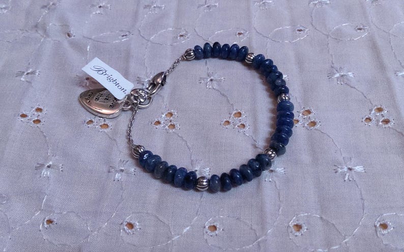 Puede incluir: Una pulsera de cuentas azules con detalles plateados y un dije en forma de coraz&oacute;n. La pulsera presenta peque&ntilde;as cuentas azules redondas y cuentas plateadas. Una etiqueta con la palabra "Brighton" est&aacute; adjunta.