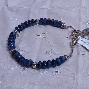 Puede incluir: Una pulsera de cuentas azules con detalles plateados. La pulsera presenta peque&ntilde;as cuentas azules redondas y cuentas espaciadoras plateadas. Un dije plateado en forma de coraz&oacute;n y una etiqueta con la palabra "Brighton" est&aacute;n adjuntos.