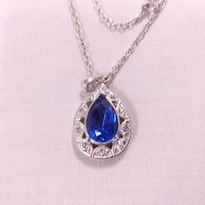 NRT Vintage Silvertone Necklace with an Oval Shaped Pendant that has a Cobalt Blue Glass Stone surrounded by Clear Rhinestones.