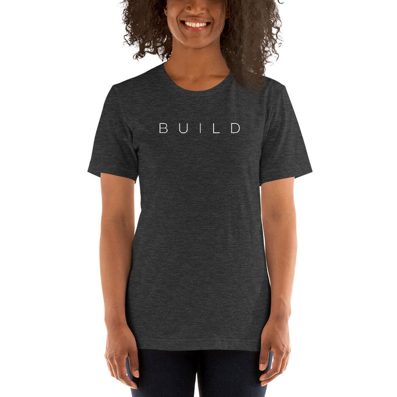 May include: A dark heather grey t-shirt with the word "BUILD" printed in white on the front.