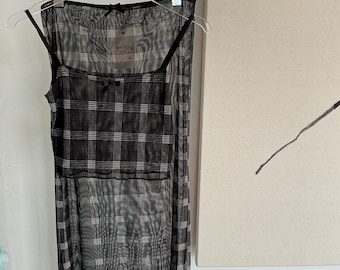 Könnte beinhalten: Schwarzes und weißes kariertes Netz-Slipdress mit quadratischem Ausschnitt und dünnen Trägern. Das Kleid hat einen durchsichtigen Überzug mit einem karierten Muster.
