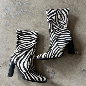 Könnte beinhalten: Ein Paar schwarze und weiße Stiefeletten mit Zebra-Muster und Blockabsatz.