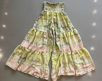 May include: A pair of wide-leg pants in a light green and pink floral pattern. The pants have a smocked waistband and tiered ruffles. The fabric appears lightweight and flowy, suitable for warm weather.