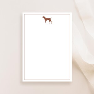 May include: A white notepad with a brown dog silhouette in the top center. The notepad has a thin brown border.