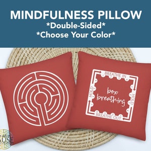 May include: Double-sided red pillow with two designs. One side features a white labyrinth design. The other side features a white box breathing diagram with the words "Breathe In", "Hold", "Box Breathing", and "Breathe Out".