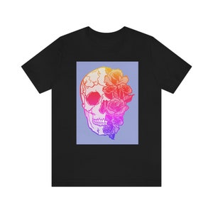 May include: Black t-shirt with a graphic of a skull with flowers covering one eye. The skull and flowers are in a gradient of pink, orange, and yellow.