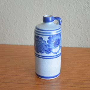 May include: A blue and white ceramic pitcher with a floral design. The pitcher has a handle and a spout.