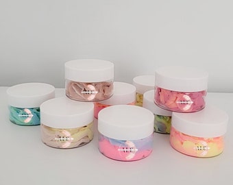 Può includere: Otto piccoli barattoli bianchi con coperchi pieni di slime colorato. Lo slime è marmorizzato con diversi colori, tra cui rosa, blu, giallo e verde.