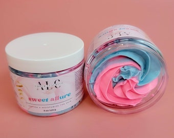 May include: Two clear jars of body butter with white lids. One jar is upright, the other is on its side, revealing pink and blue swirls of product. The label reads "sweet allure" and "soften & moisturize the skin". Each jar contains 6 oz / 170 g.