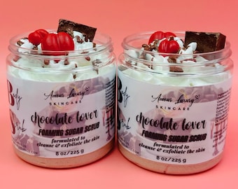 May include: Two jars of chocolate lover foaming sugar scrub, each with a white lid and a brown label. The label says "Amour Luxury Skincare" and "chocolate lover foaming sugar scrub" with the tagline "formulated to cleanse & exfoliate the skin". The jars are 8 oz/225 g.