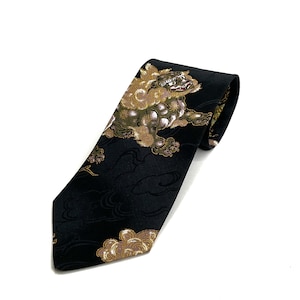 May include: Black necktie featuring a detailed illustration of a mythical creature in shades of gold, brown, and white. The tie has a repeating cloud pattern. The tie is made of a smooth, likely silk, material.