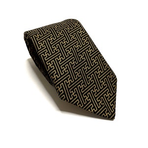May include: A black tie with a gold geometric pattern. The pattern is a repeating design of squares and rectangles.