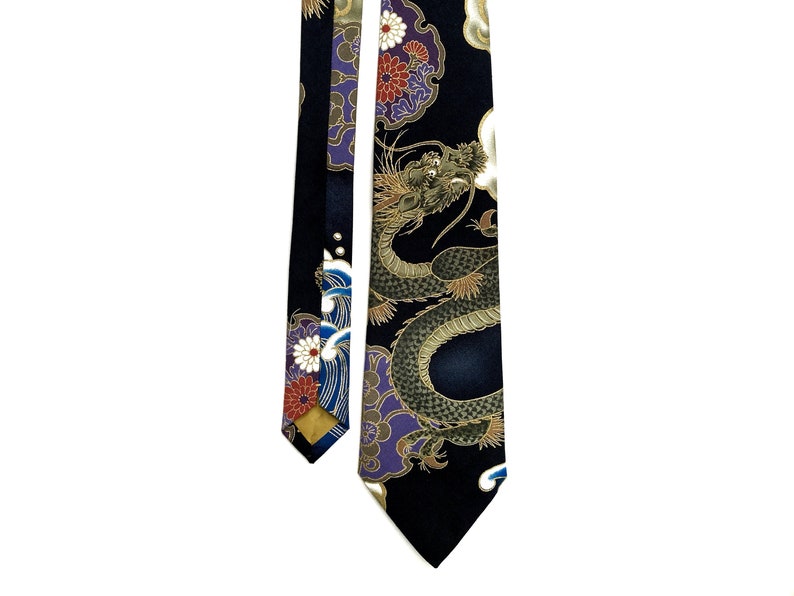 Peut inclure: Une cravate en soie noire avec un motif de dragon dor&eacute; et vert. Le dragon est entour&eacute; de nuages et de fleurs. La cravate est r&eacute;versible et pr&eacute;sente un motif floral de l'autre c&ocirc;t&eacute;.