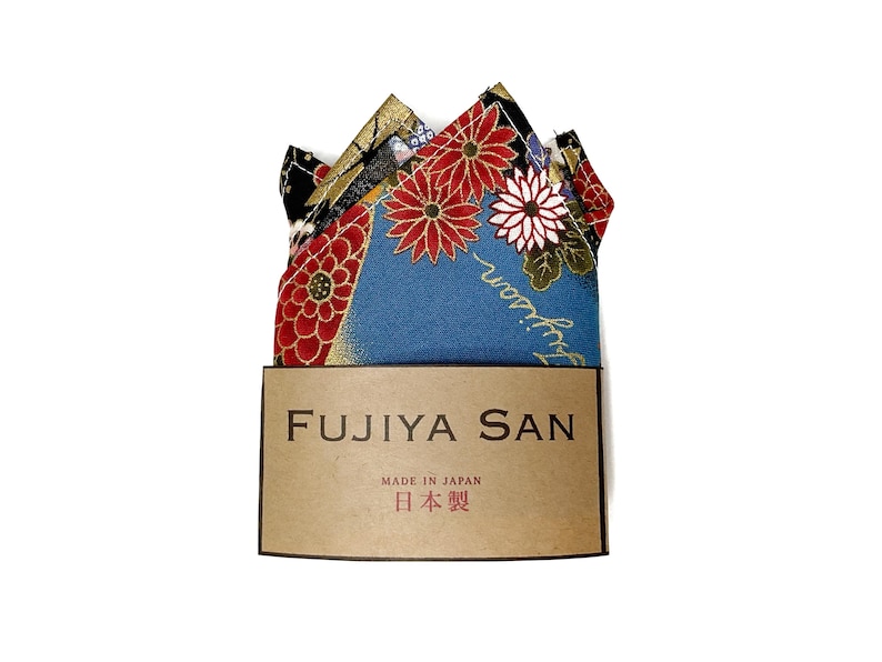 May include: A folded pocket square with a floral pattern in red, white, and gold on a blue background. The pocket square is displayed with a brown tag that reads "FUJIYA SAN" and "MADE IN JAPAN" with Japanese text.