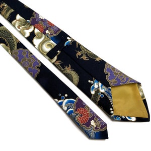 Peut inclure: Une cravate en soie bleu fonc&eacute; avec un motif de dragon, de nuage et de fleur dor&eacute;s et violets. La cravate est doubl&eacute;e d'or.
