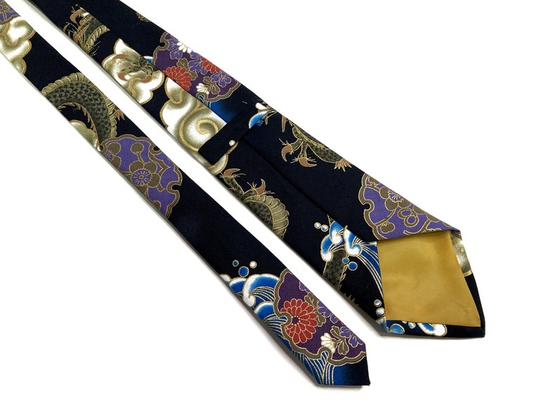 Peut inclure: Une cravate en soie bleu fonc&eacute; avec un motif de dragon, de nuage et de fleur dor&eacute;s et violets. La cravate est doubl&eacute;e d'or.