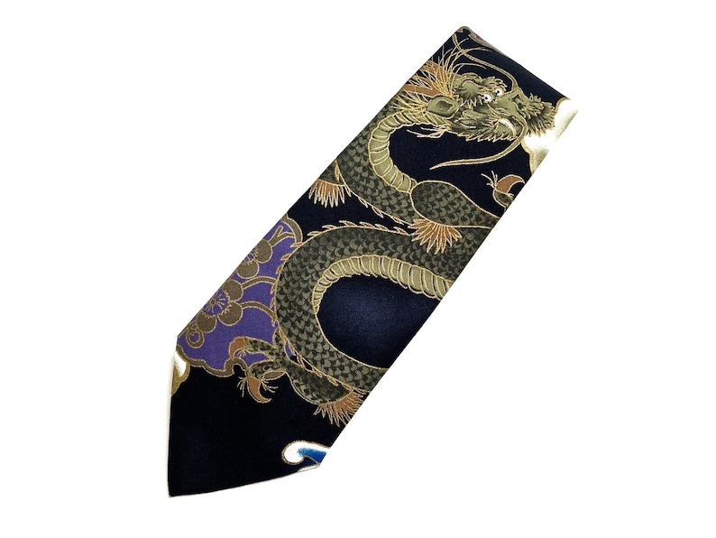 Peut inclure: Une cravate en soie bleu fonc&eacute; avec un motif de dragon dor&eacute; et vert. Le dragon est repr&eacute;sent&eacute; dans une pose tourbillonnante et dynamique, la t&ecirc;te tourn&eacute;e vers le spectateur.