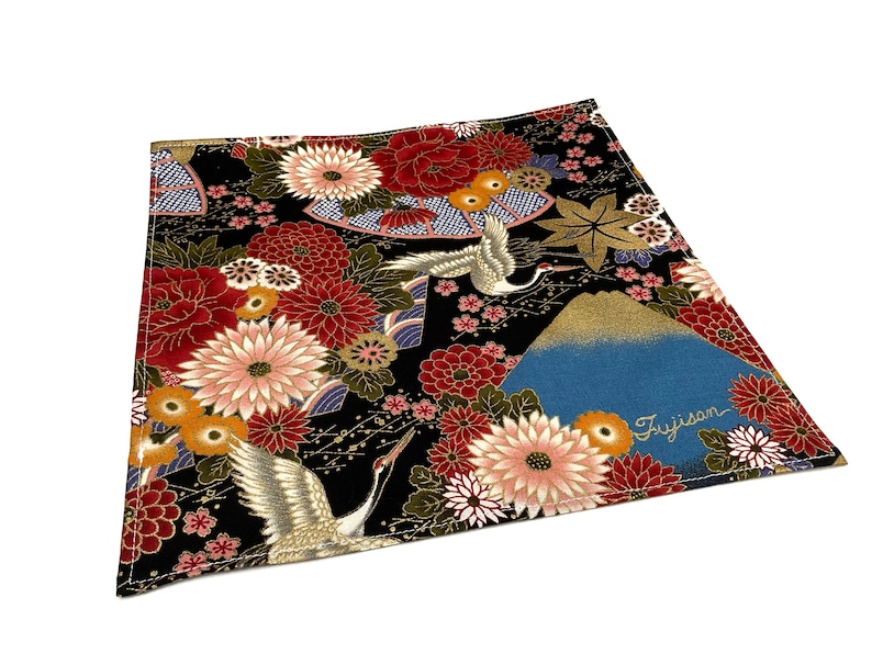 May include: Square fabric with a Japanese-inspired design. The black background is covered with red, pink, and gold floral patterns, with images of cranes and Mount Fuji. The word "Fujisan" is written on the fabric.