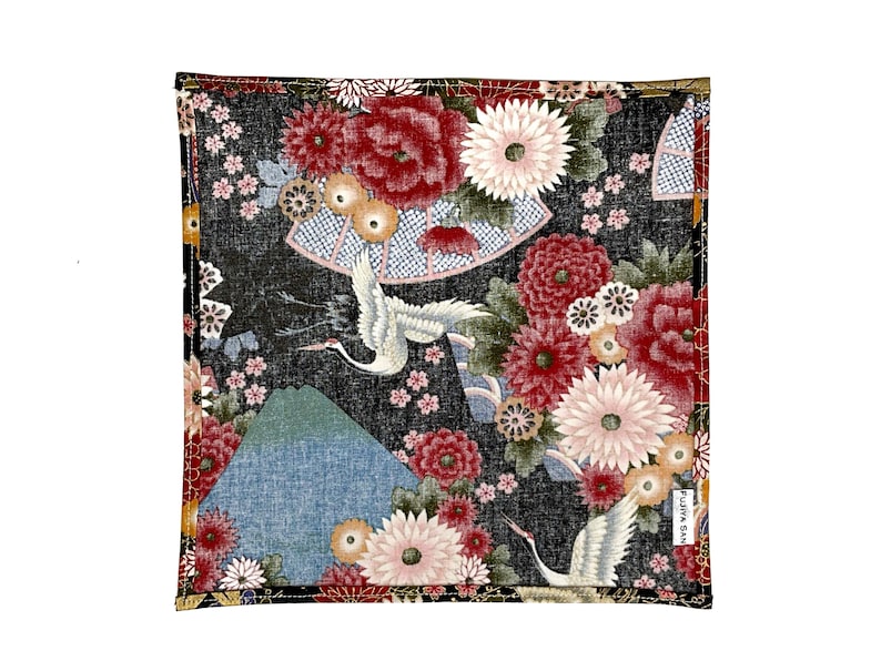 May include: Square fabric with a Japanese-inspired design. The black background is covered with red, pink, and white flowers, cranes, and a mountain. The design includes a fan and small text in the bottom right corner.