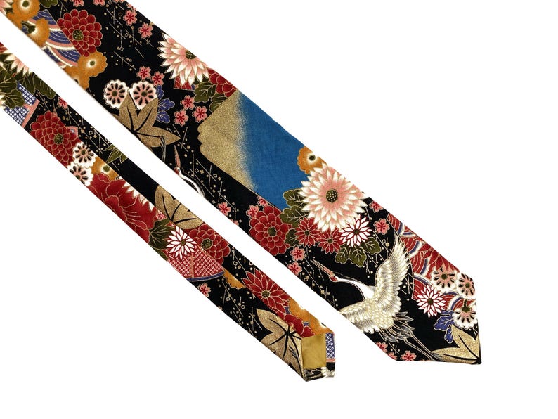 May include: A necktie featuring a black background with a vibrant pattern of red, white, and pink chrysanthemums, gold maple leaves, and a white crane in flight. The design includes blue accents and intricate gold detailing throughout the fabric.