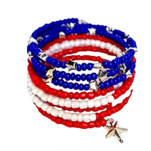 May include: A red, white, and blue beaded bracelet with silver stars. The bracelet is wrapped in a spiral pattern and has a silver star charm.