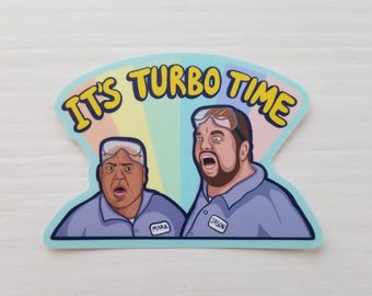 May include: A sticker featuring two cartoon men with surprised expressions, wearing goggles and light blue shirts. The text "IT'S TURBO TIME" is in yellow, outlined in black, above them. The background is a rainbow.