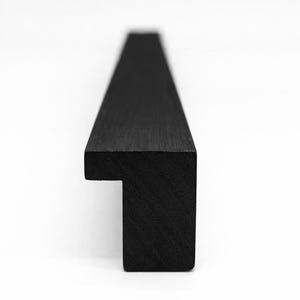 May include: A black wooden picture frame profile, seen from the side, against a white backdrop. The frame is rectangular with a step detail at the end. The wood grain is visible. The frame's dimensions are in centimetres.
