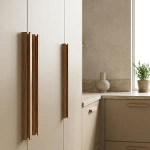May include: Long, vertical, light brown wooden cabinet handles with a grooved, linear design attached to tall, matte beige kitchen cabinetry. The handles feature a rectangular profile and are mounted on the flat, seamless doors of the kitchen unit.