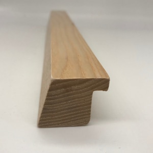 May include: A close-up of a light brown wooden picture frame with a simple, rectangular design. The frame is made of solid wood and has a smooth finish.