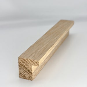 May include: A light brown wooden cabinet pull with a T-shaped design. The pull is made of solid wood and has a natural finish.