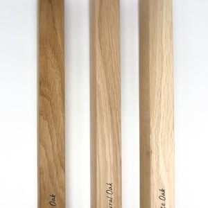 Könnte beinhalten: Drei Holzproben aus Eichenholz in verschiedenen Ausführungen: dunkle Eiche, natürliche Eiche und weiße Eiche. Die Holzproben sind vertikal angeordnet und mit ihren jeweiligen Ausführungen beschriftet.