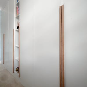 May include: White cupboard doors with a wood grain handle. The doors are closed and the handle is on the right side of the door.