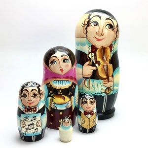 以下が含まれることがあります： 音楽家を描いた、手描きのロシアの入れ子人形、マトリョーシカ人形のセット。 最大の人形はバイオリン奏者を特徴とし、他の人形は楽譜や楽器を持っています。 人形は黒、茶色、クリーム色など、さまざまな色で塗装されています。